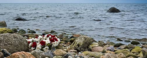 Blumenkranz mit weißen und roten Rosen an Meeresküste
